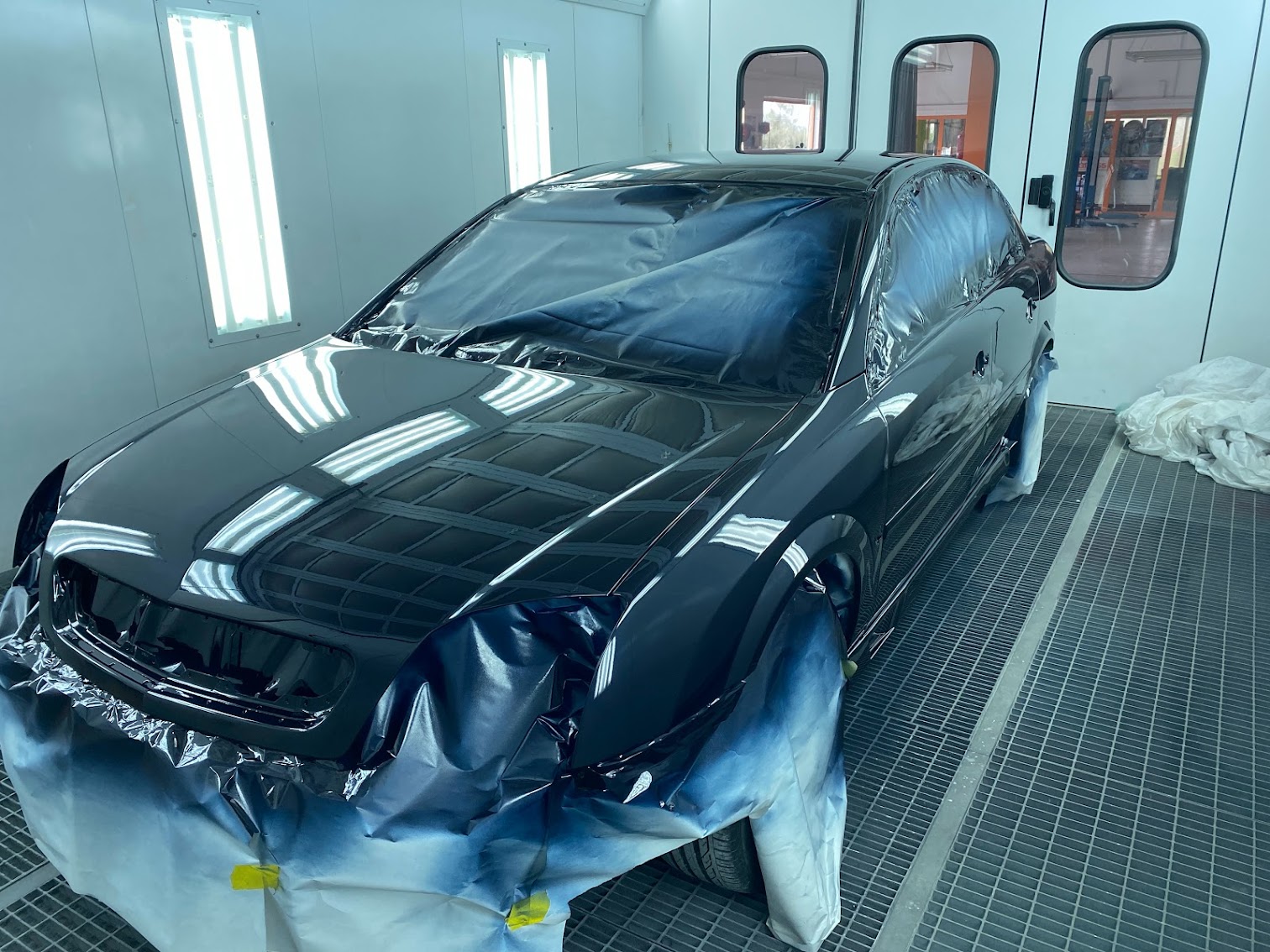 Black sedan freshly painted in booth