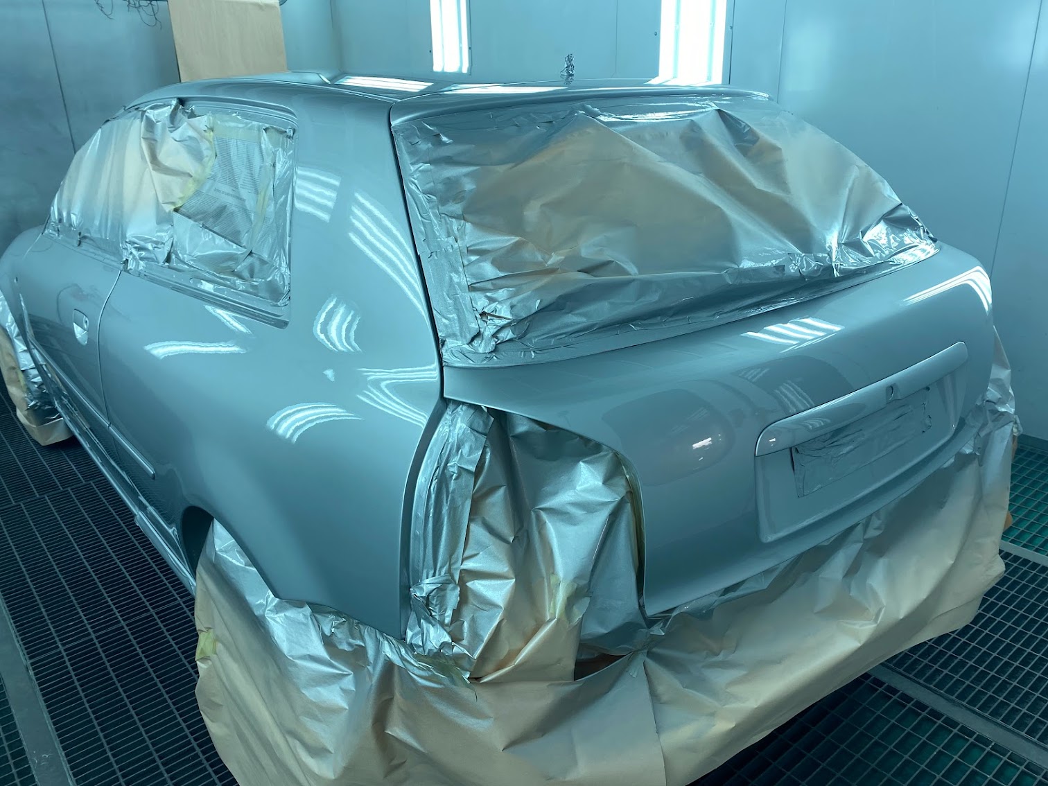 Silver car being resprayed in paint booth